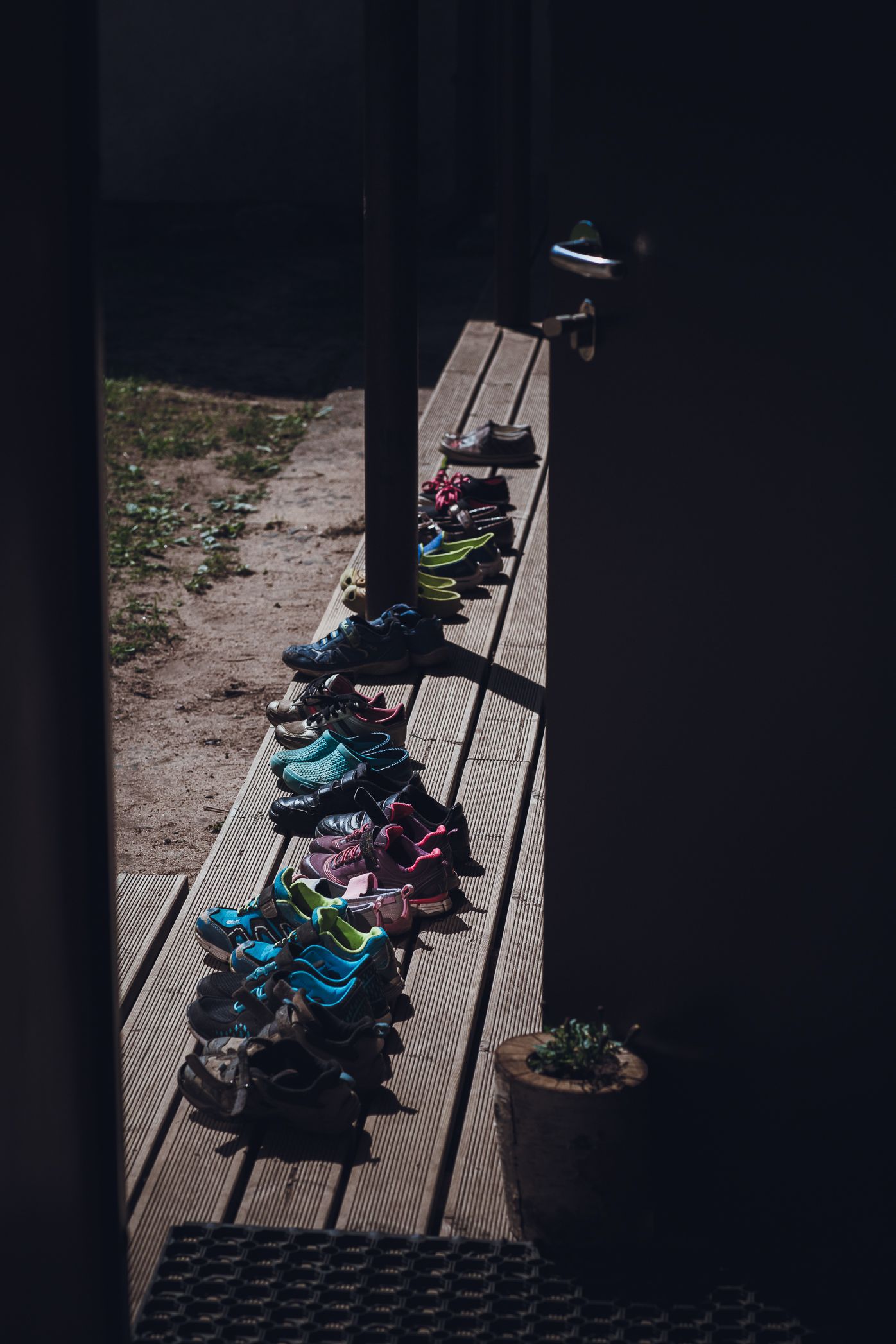 Row of colorful shoes lined up on a wooden bench in sunlight.