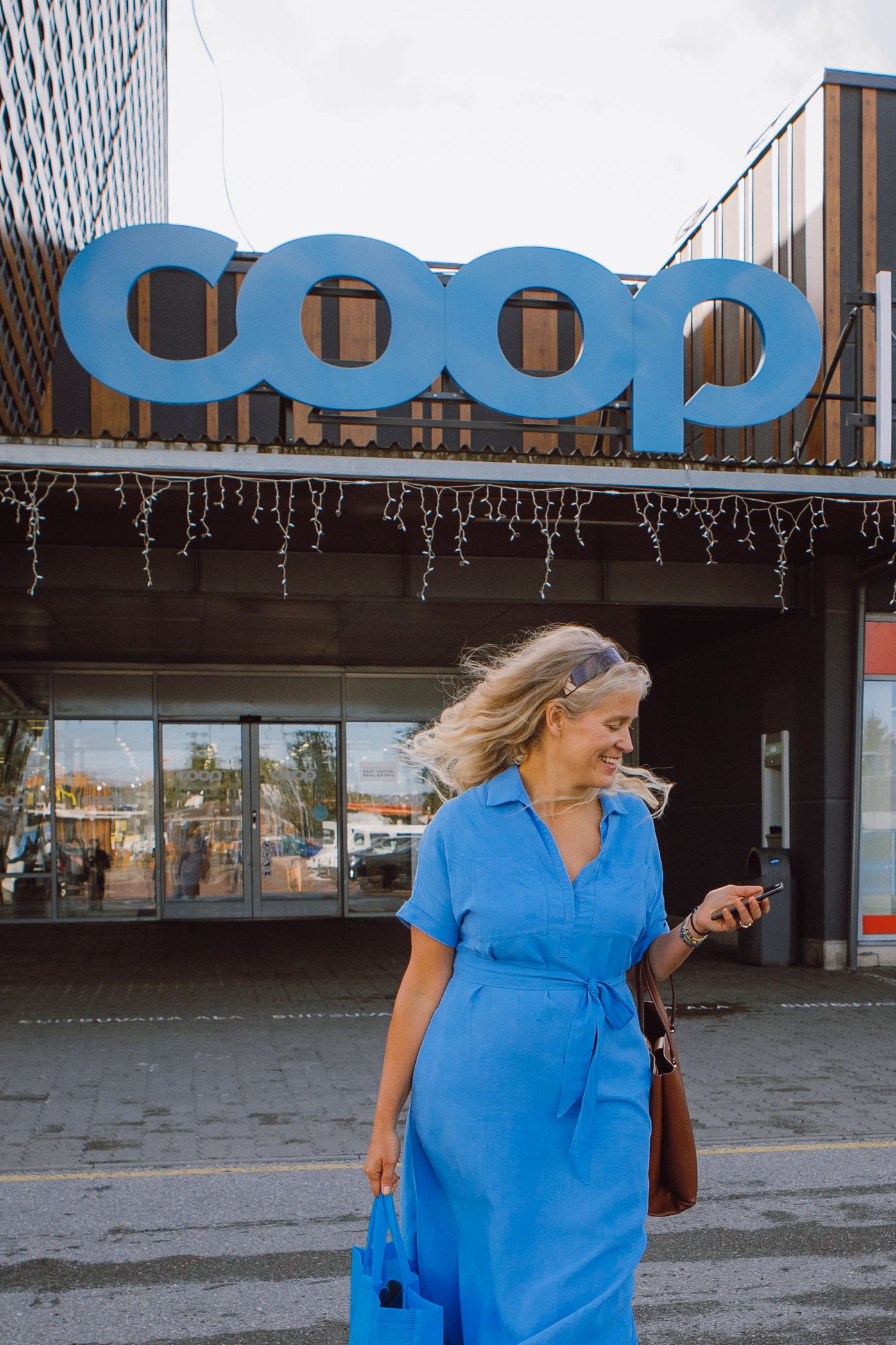 Woman in blue dress walking past urban building with large signage.