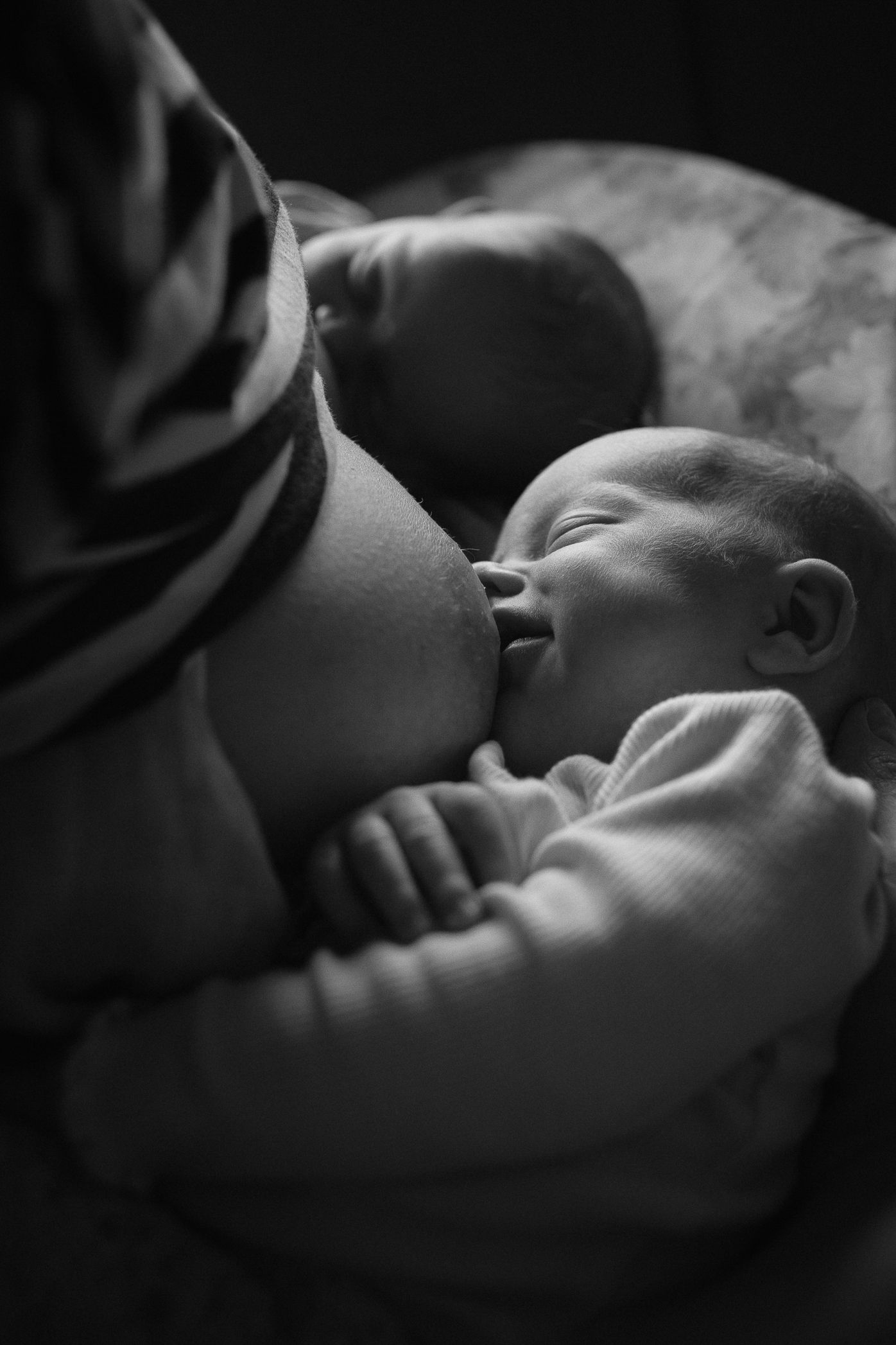 Intimate black and white photo of a newborn breastfeeding.