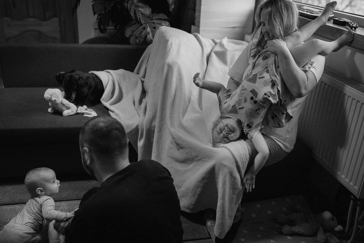 A candid black and white family scene in a living room.