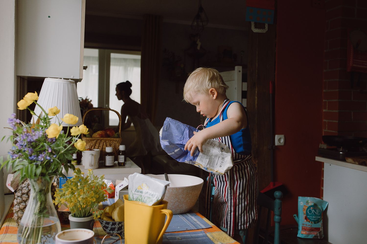 Interior view of a kitchen with sunlight streaming through windows and flowers on the counter.