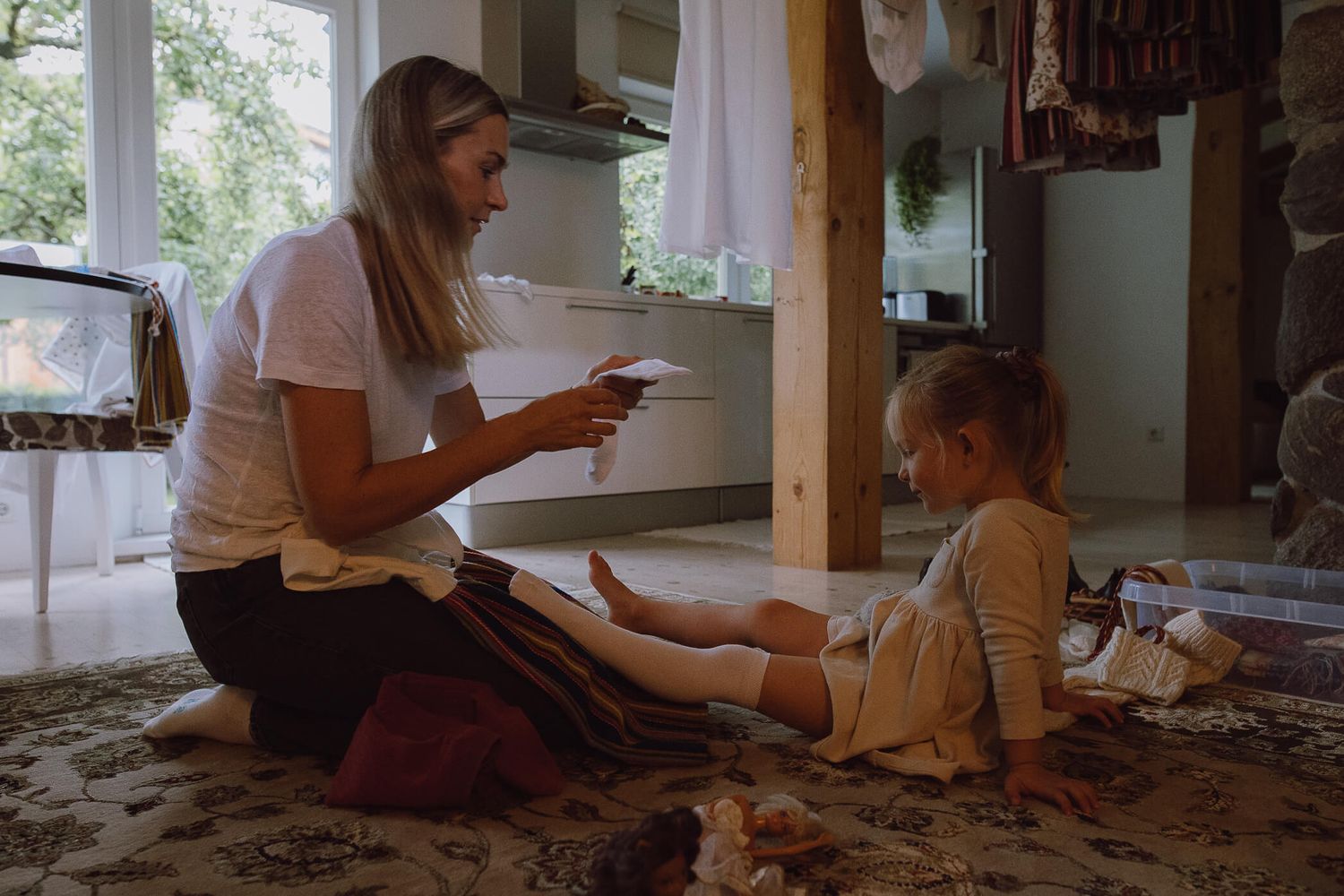 Woman reading to young girl sitting on floor in cozy rustic living room.