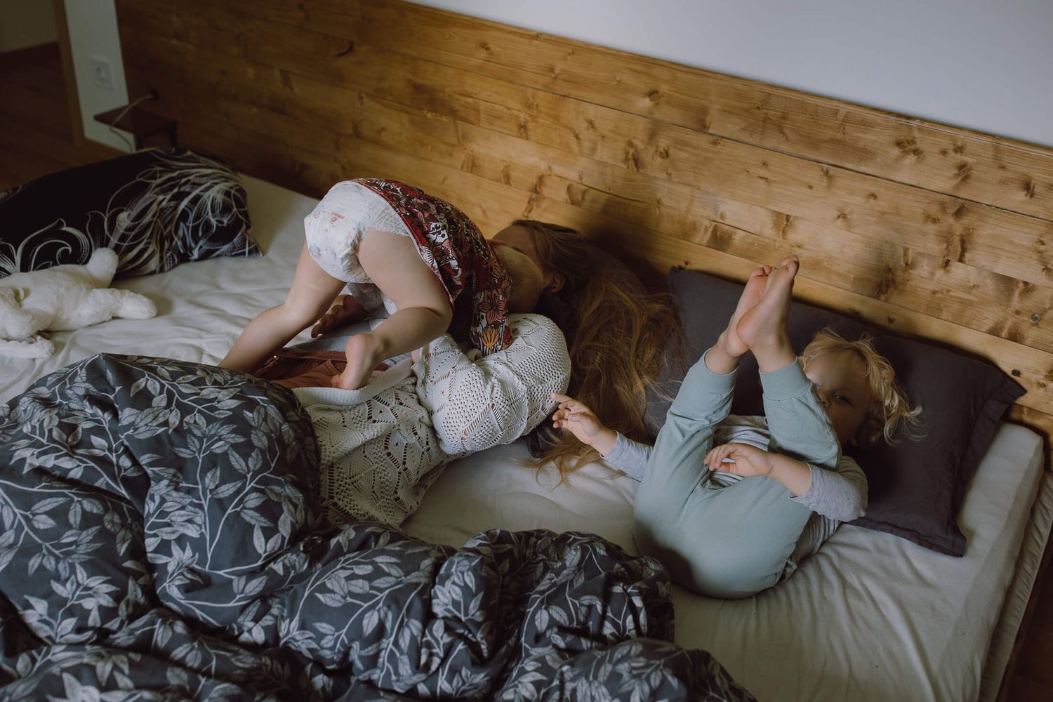 Multiple figures resting on a wooden floor with patterned blankets.