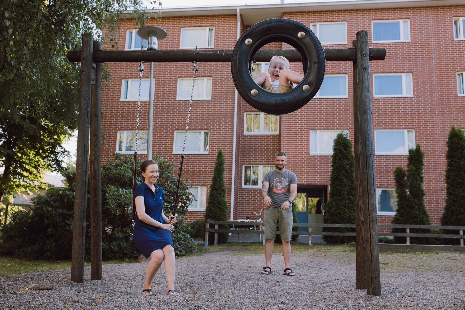 Kids playing on outdoor playground equipment near apartment buildings.