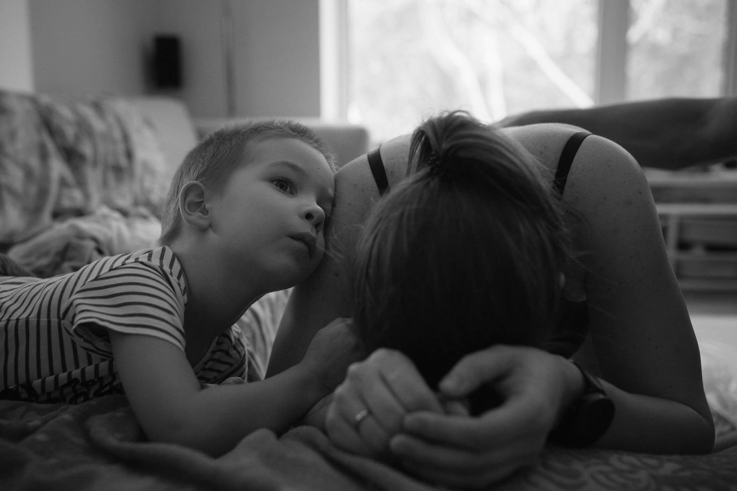 A tender black and white moment of intimate connection and rest on a bed.