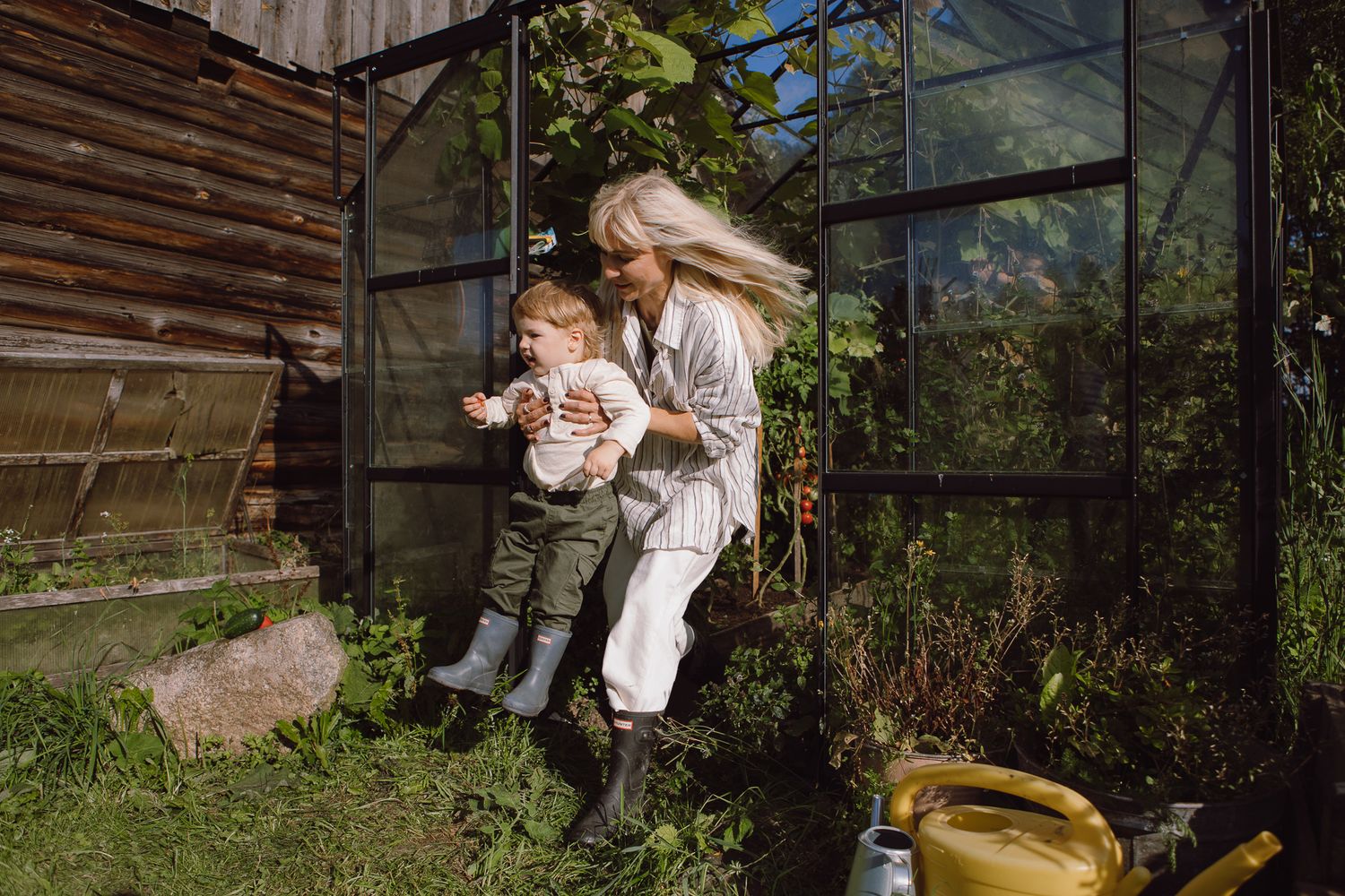 A sunny day at the greenhouse with gardening activities and a yellow watering can visible.
