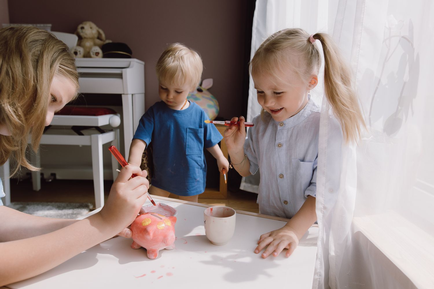 Children and adults gather around a table with a piggy bank.
