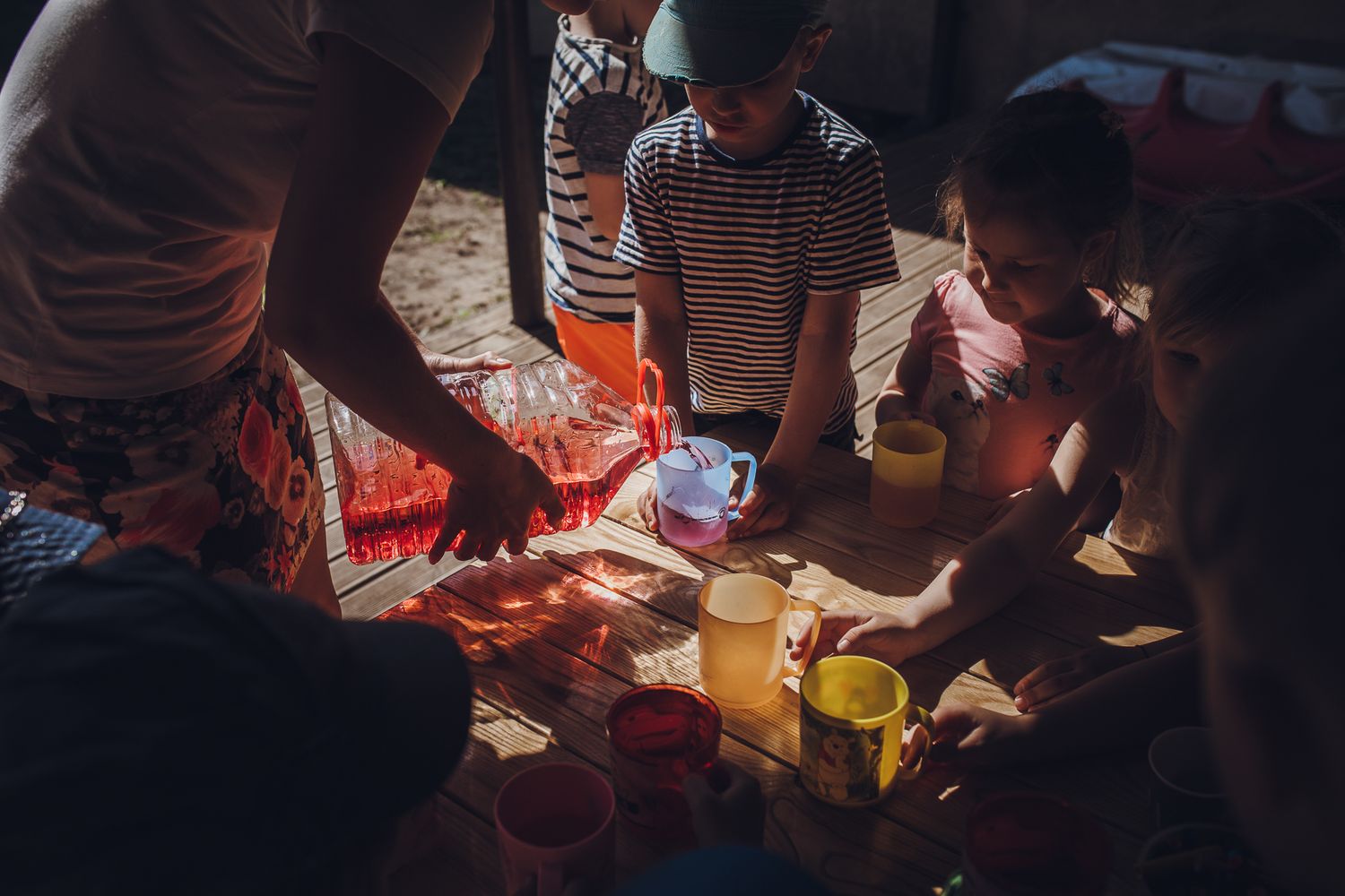 People gathered around a table with hands visible in dramatic lighting.
