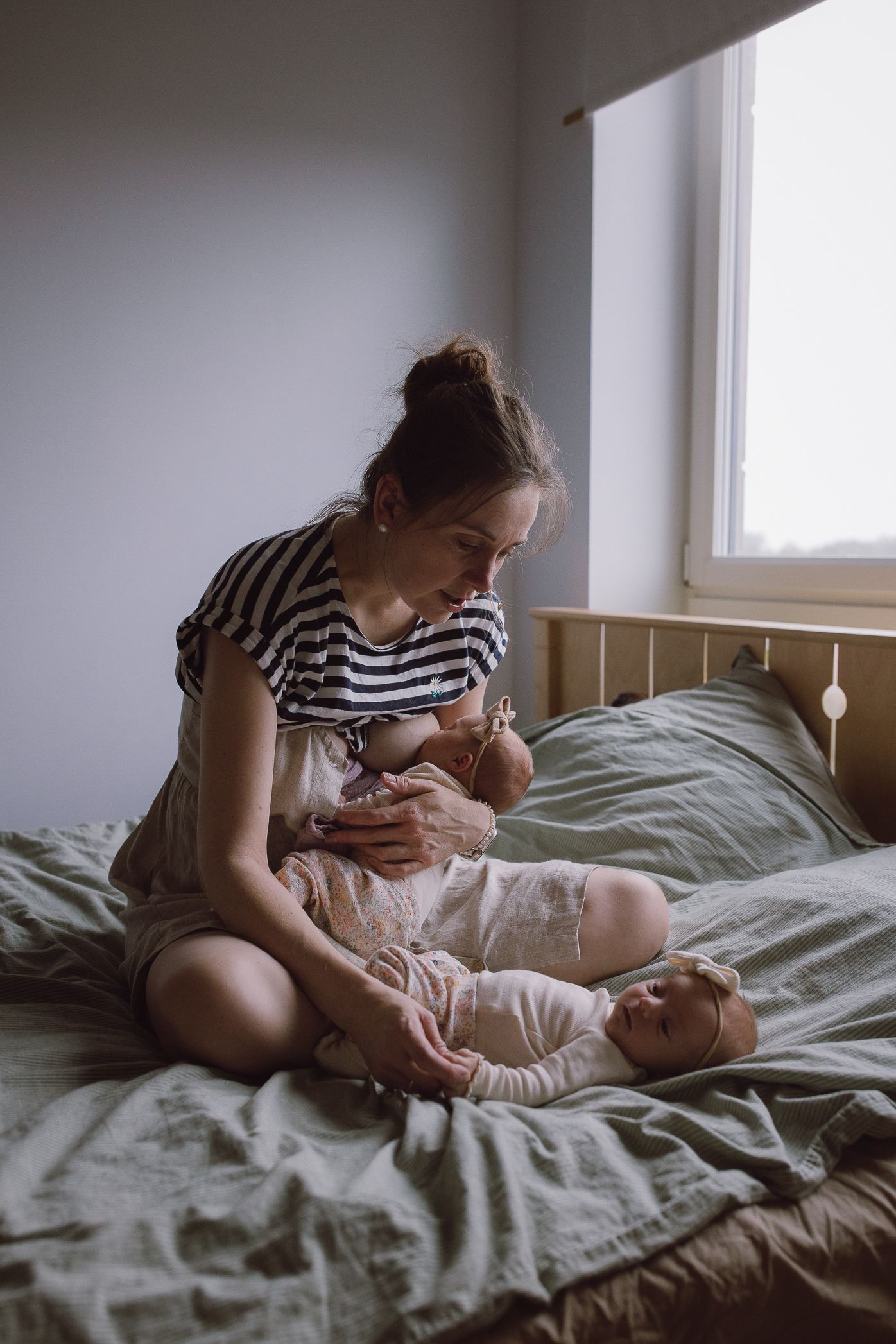 Quiet moments captured on a bed with striped clothing and natural window light.