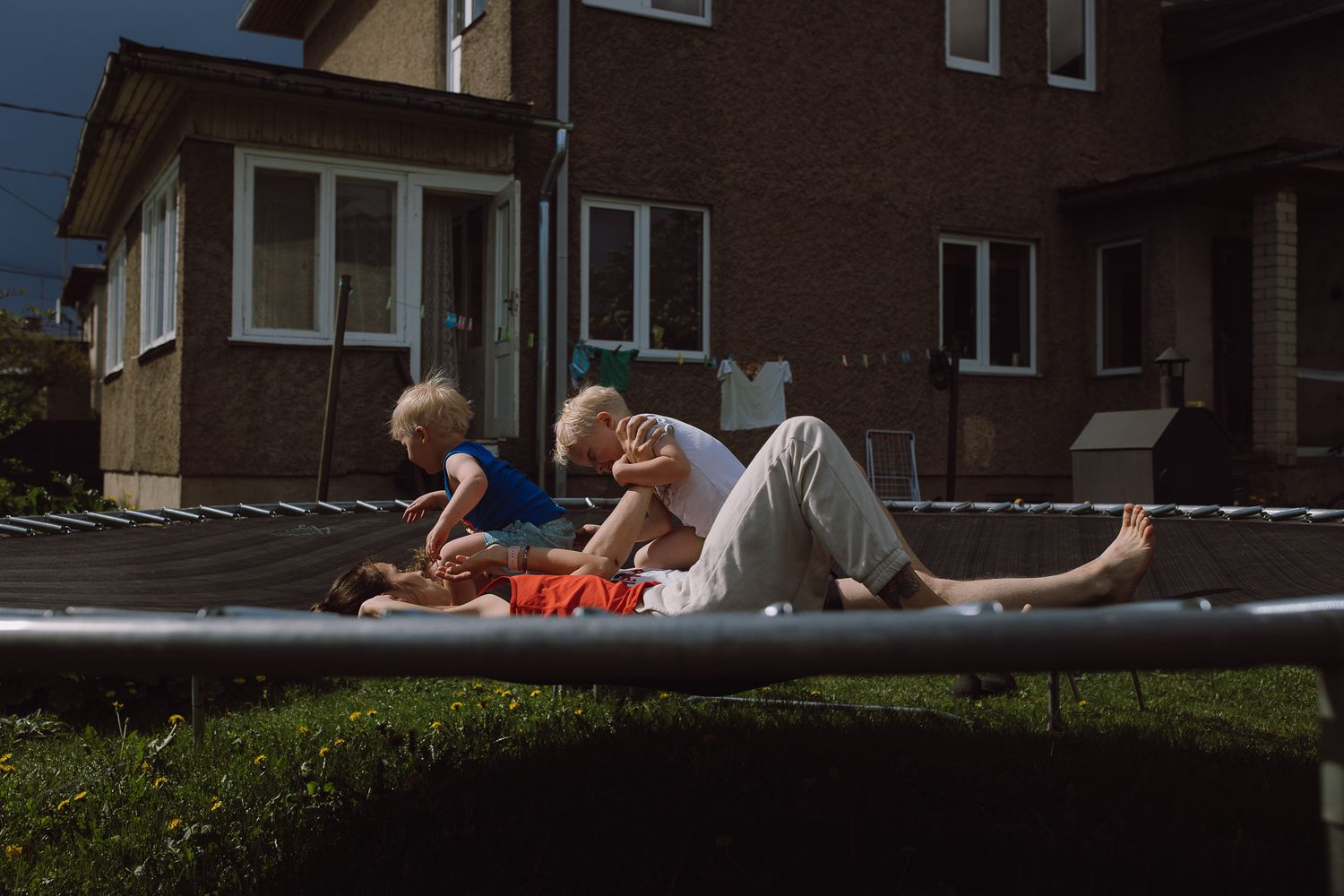 People relaxing on outdoor furniture in front of a brick house on a sunny day.