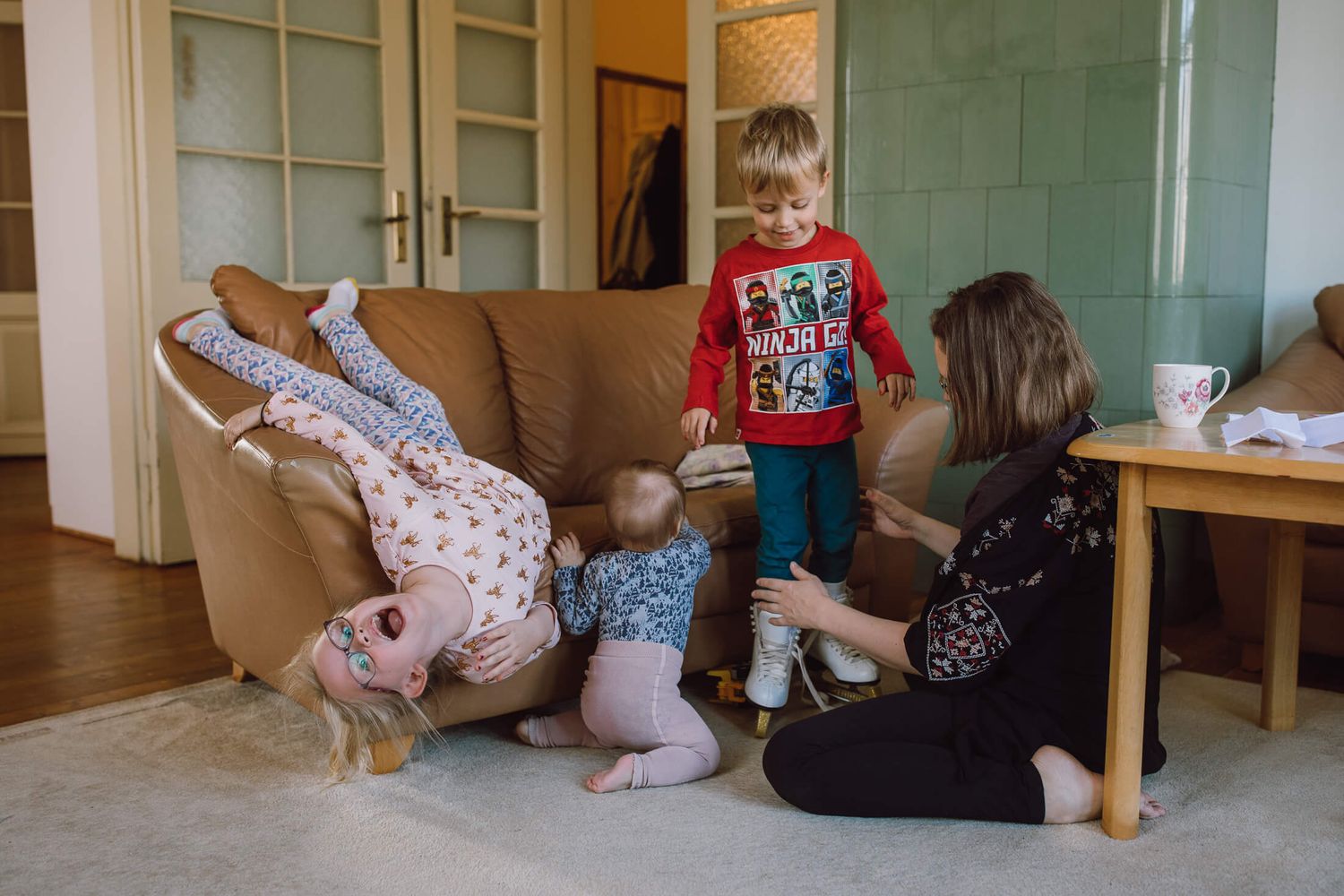 Children playing on the floor near furniture in a sunlit room.
