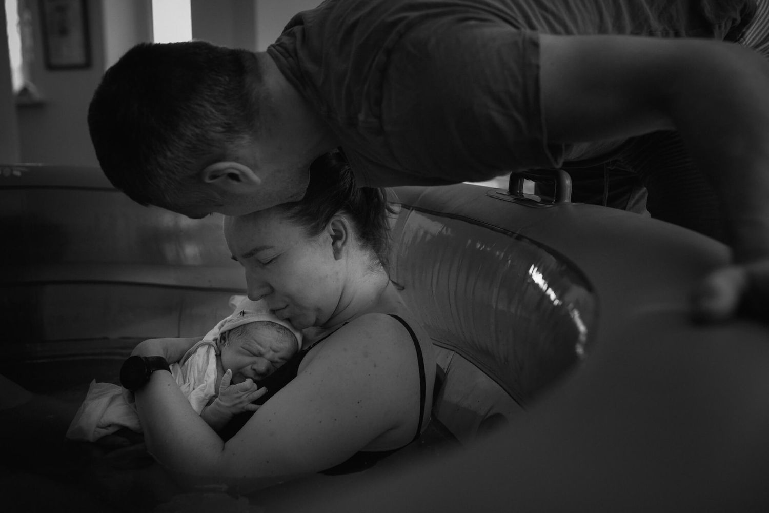 Intimate black and white photo showing support during a water birth.