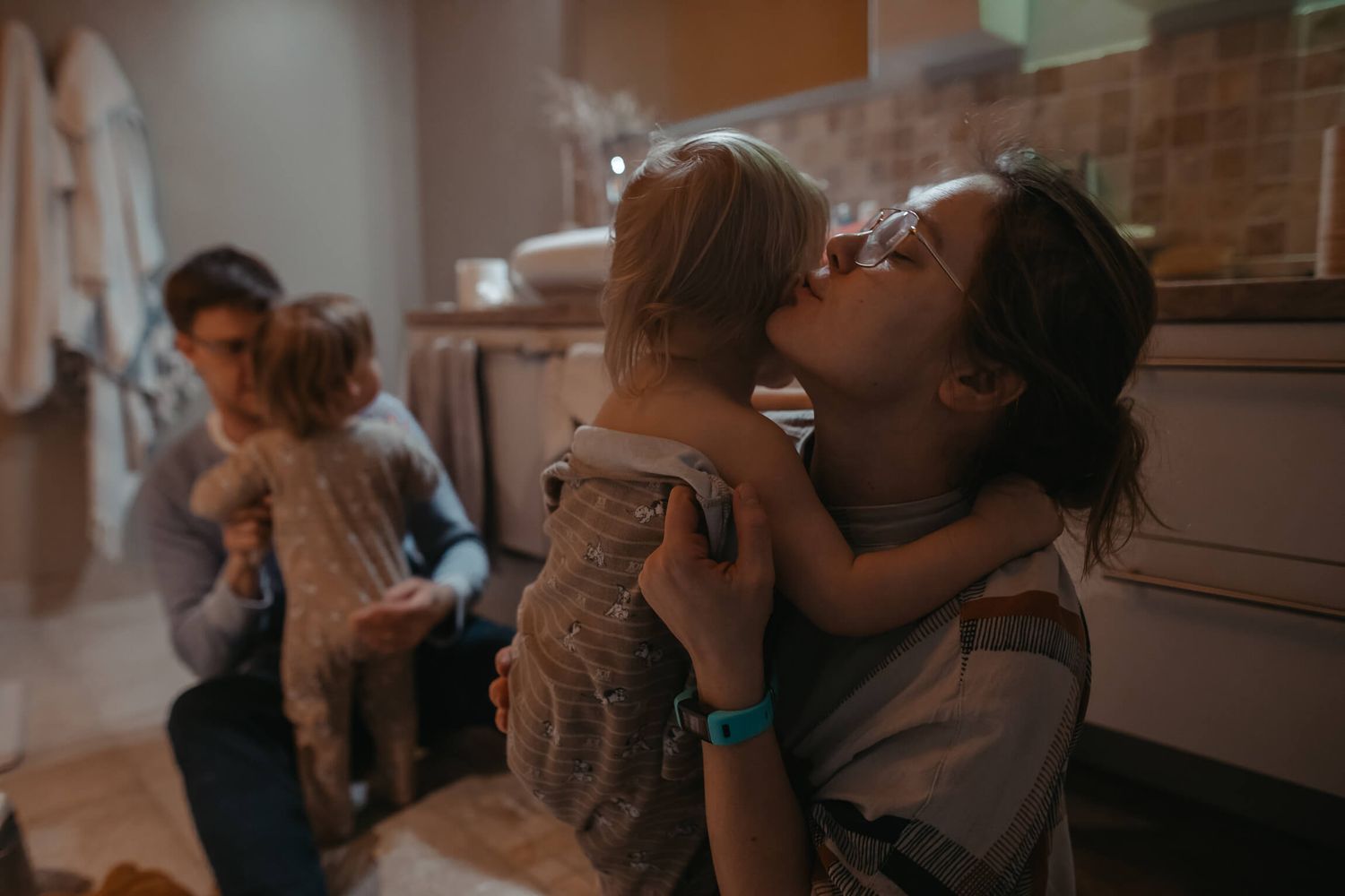 A warm, intimate scene in a kitchen with people sharing affectionate moments.