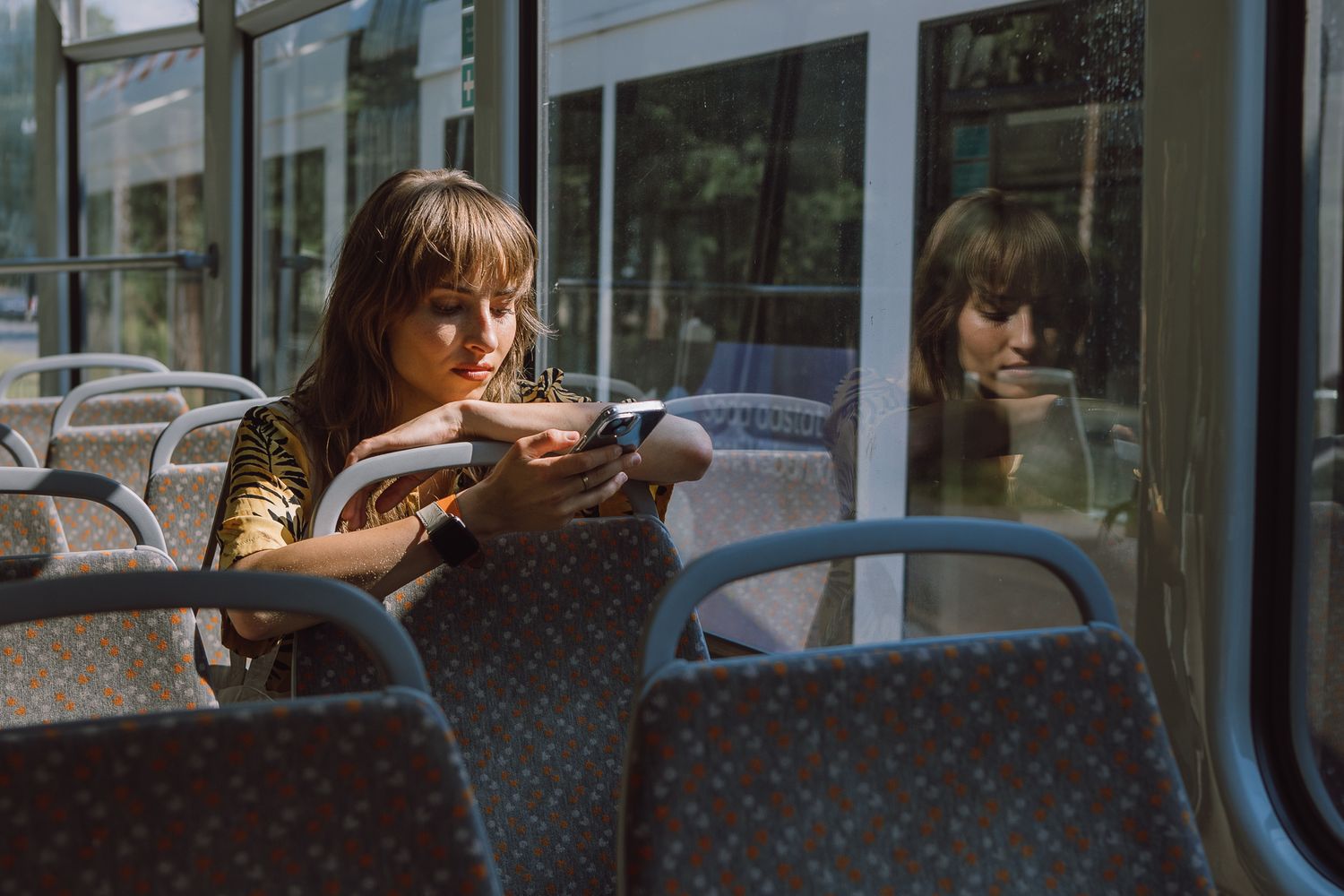 Person sitting by window on public transport looking at passing scenery.
