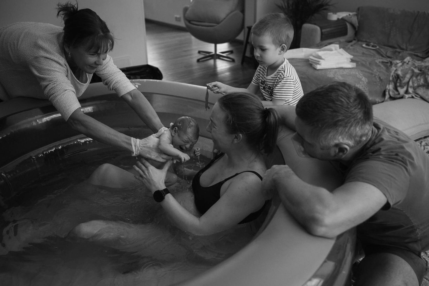 Support team assists during a water birth in an intimate home setting.