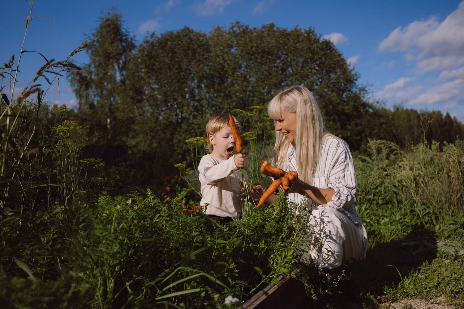 People exploring and gathering items in a lush green garden on a sunny day.