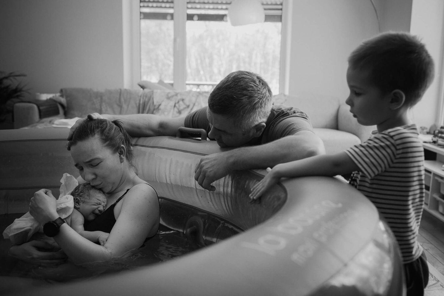 Family members provide support around a birthing pool during labor.