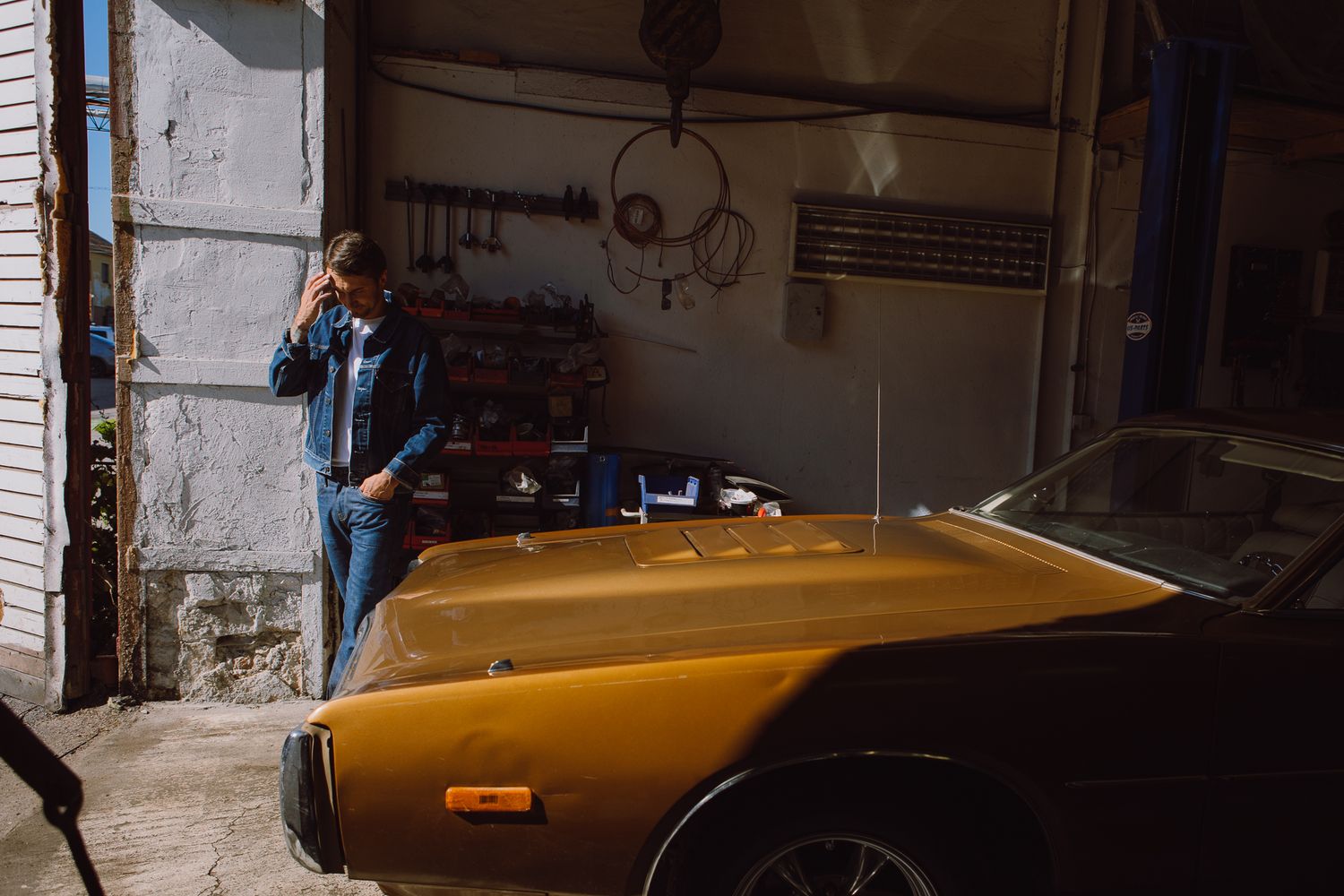 Vintage yellow muscle car being worked on in a dimly lit garage.
