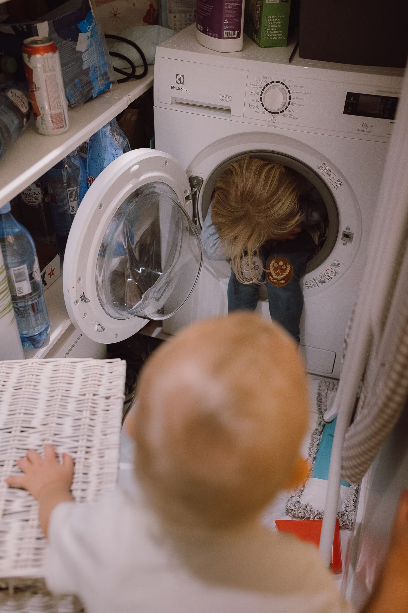 Person loading laundry into a white front-loading washing machine.