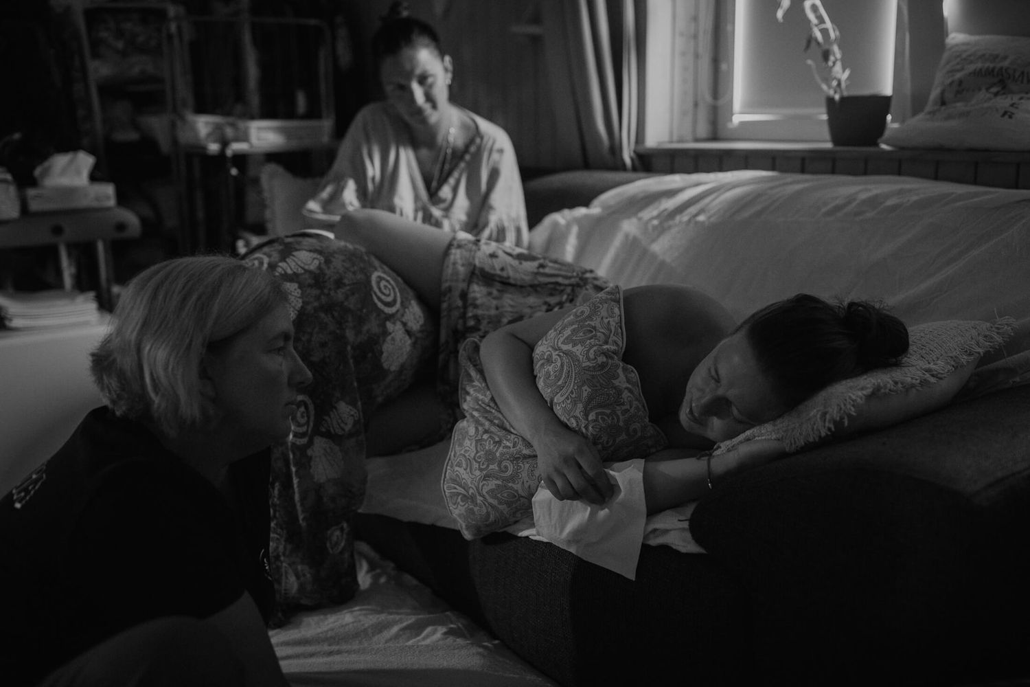 Black and white image of a medical treatment room with patient on bed.