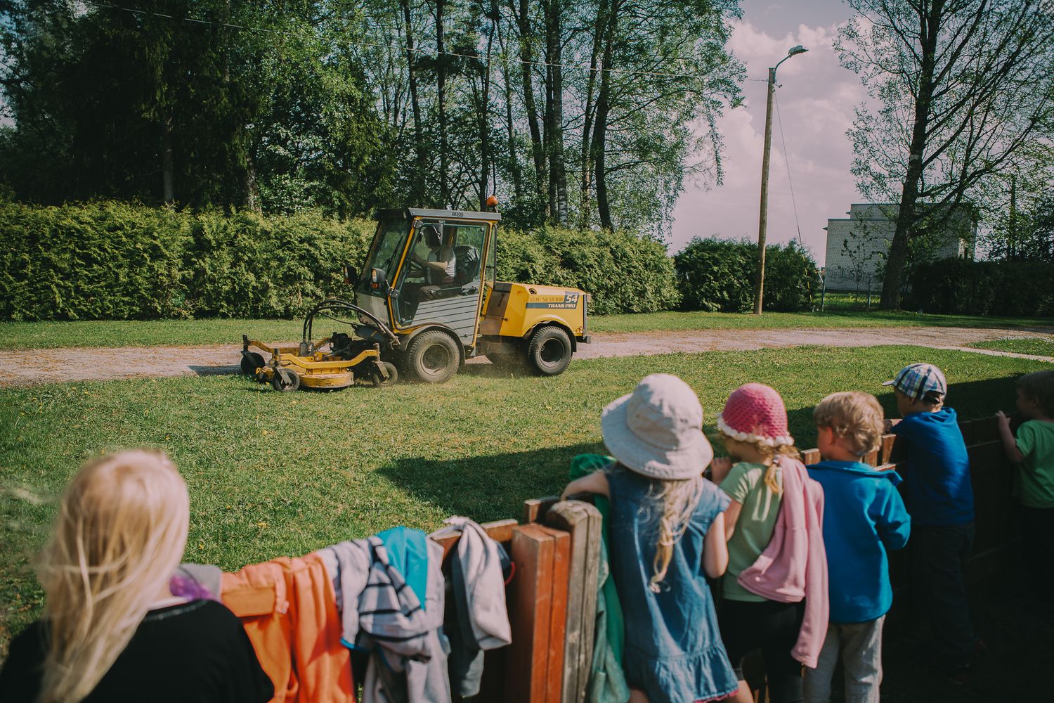 Group of children playing outdoors on a sunny day with playground equipment visible.
