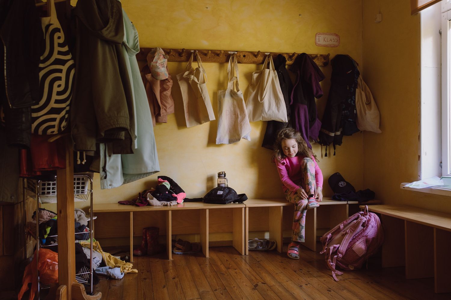 Clothing hanging on hooks in a changing room with yellow walls.