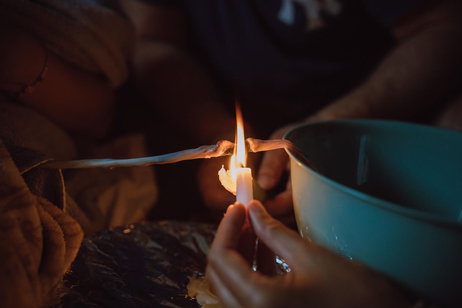 Close-up of hands holding a lit match in a dimly lit birthing environment.