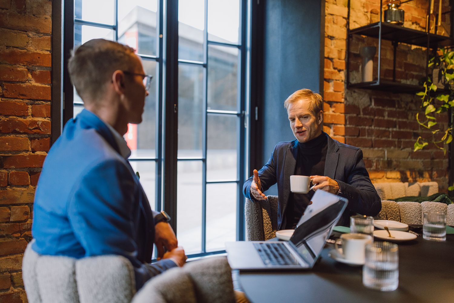Business meeting in industrial-style office with exposed brick walls and natural lighting.