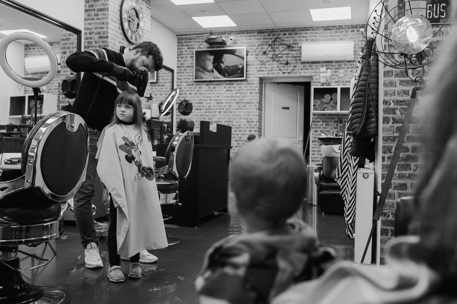 Black and white image of a busy indoor space with brick walls and industrial lighting.