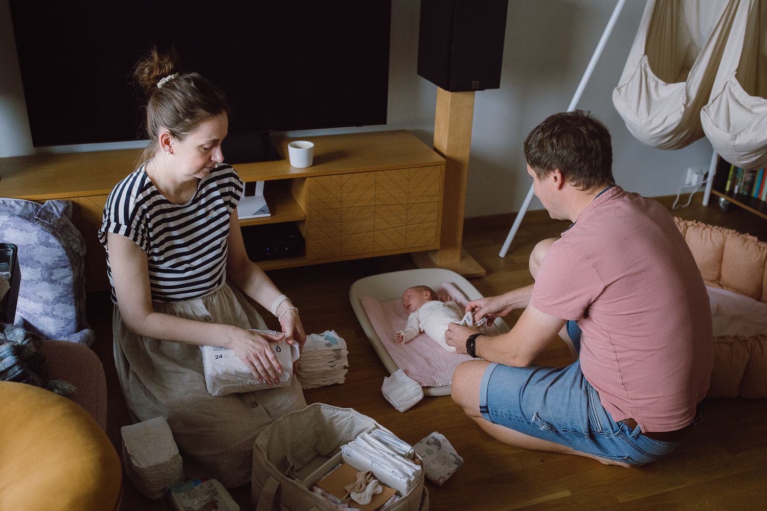 People sitting on floor cushions while caring for a baby.