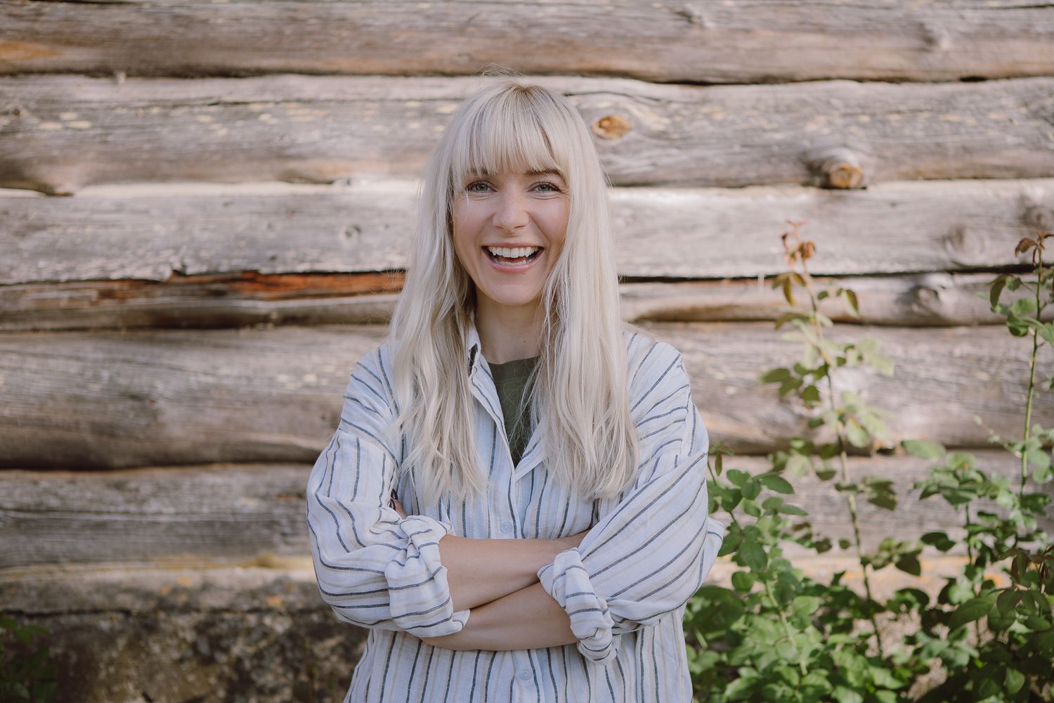 A joyful moment captured against a rustic log cabin wall with greenery.
