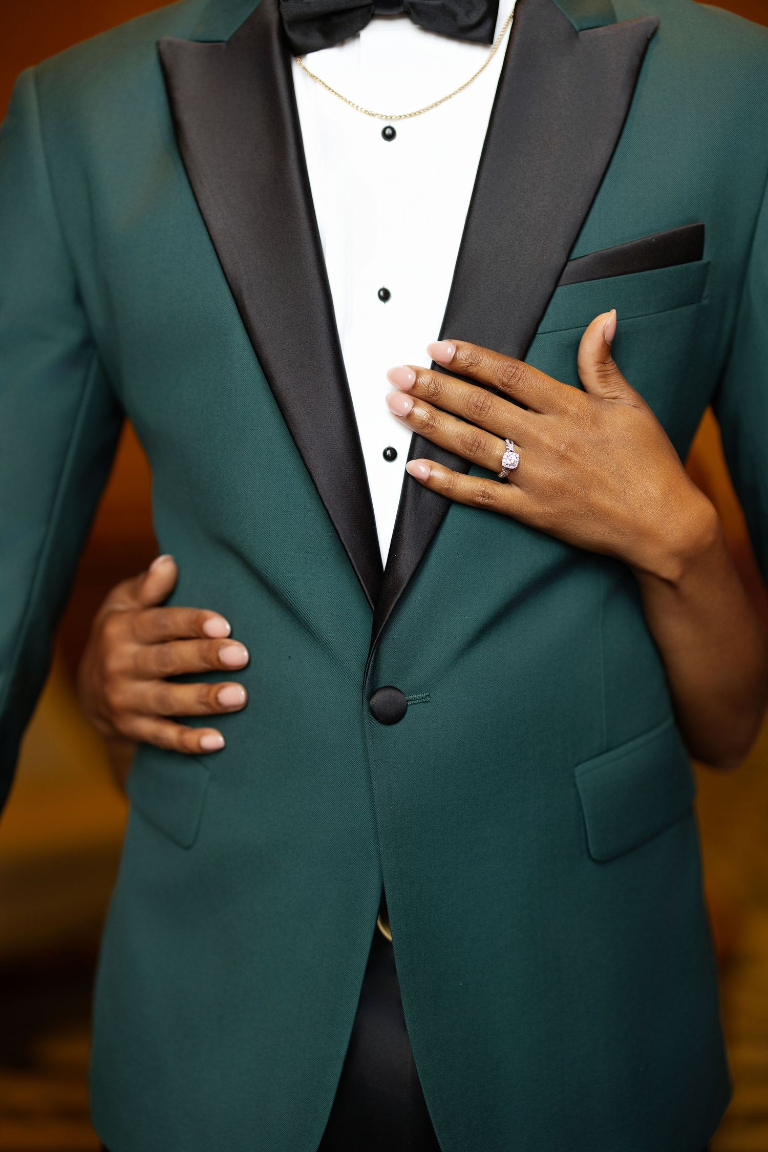 Close-up details of an emerald green suit jacket with black lapels and white dress shirt styled for formal occasions.