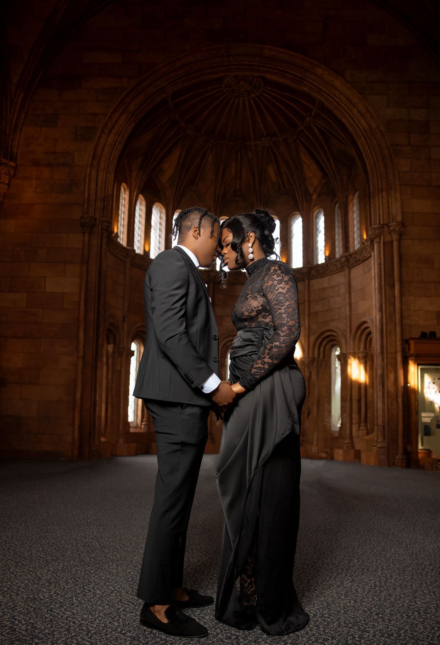 Romantic couple in formal attire share an intimate moment inside a grand cathedral with arched windows and vaulted ceiling.