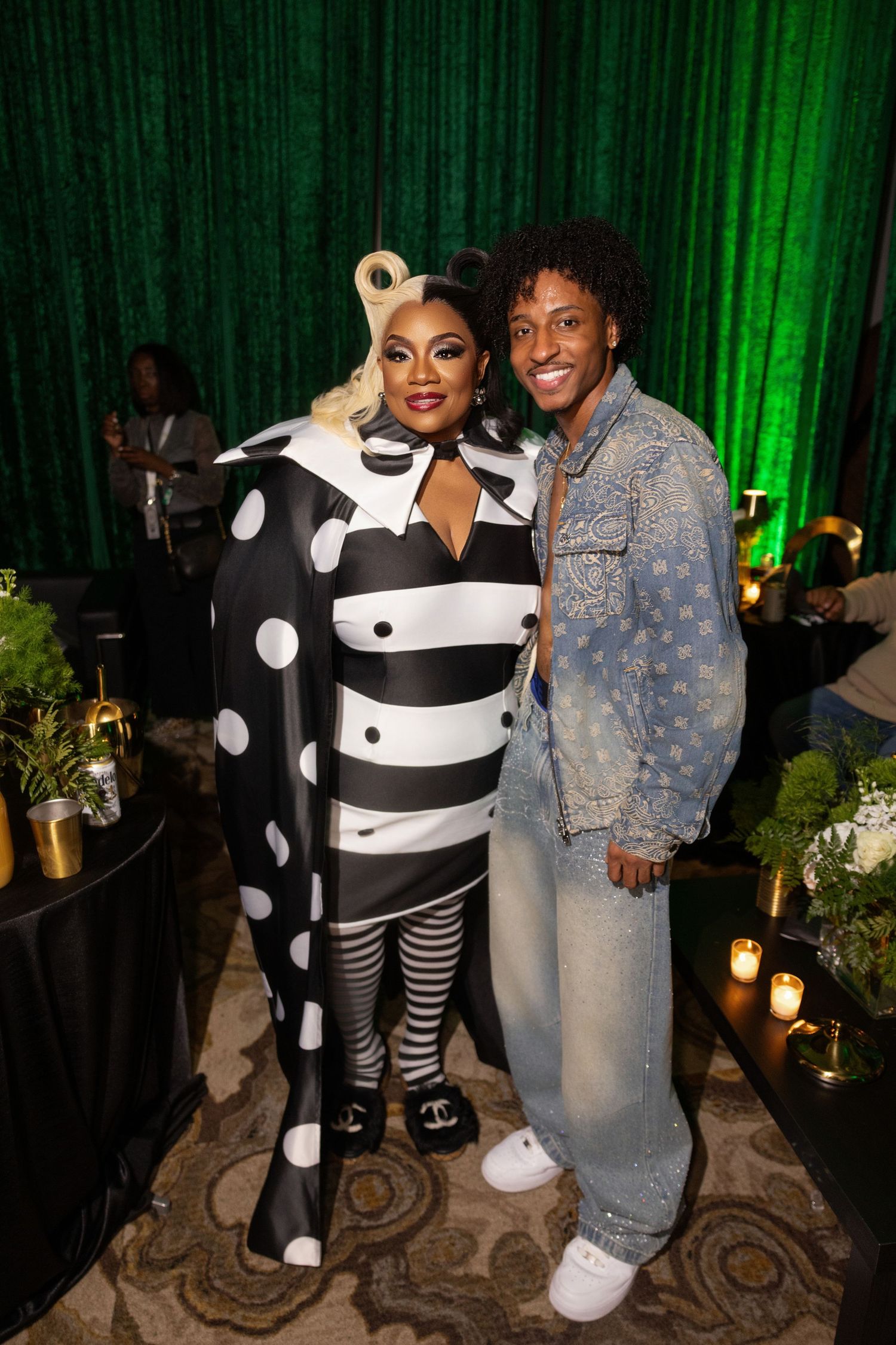 Event photo featuring black and white polka dot costume against green curtain backdrop.