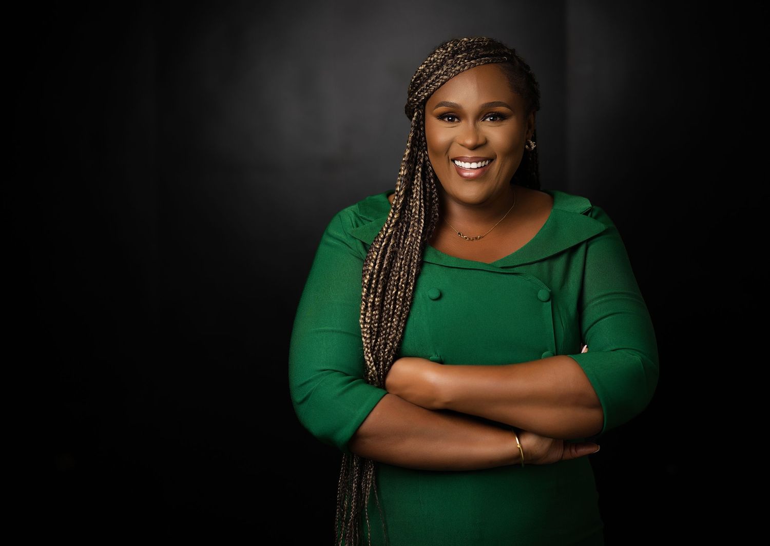 Studio headshot featuring elegant green dress against dramatic dark backdrop.