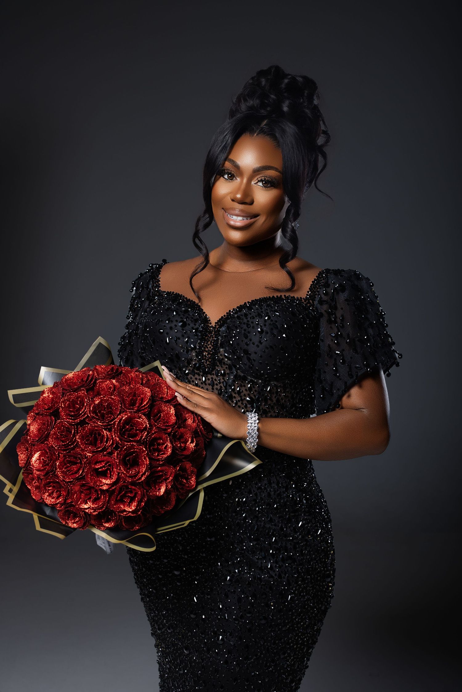 Elegant portrait session featuring a sparkly black dress and vibrant red roses against dark backdrop.