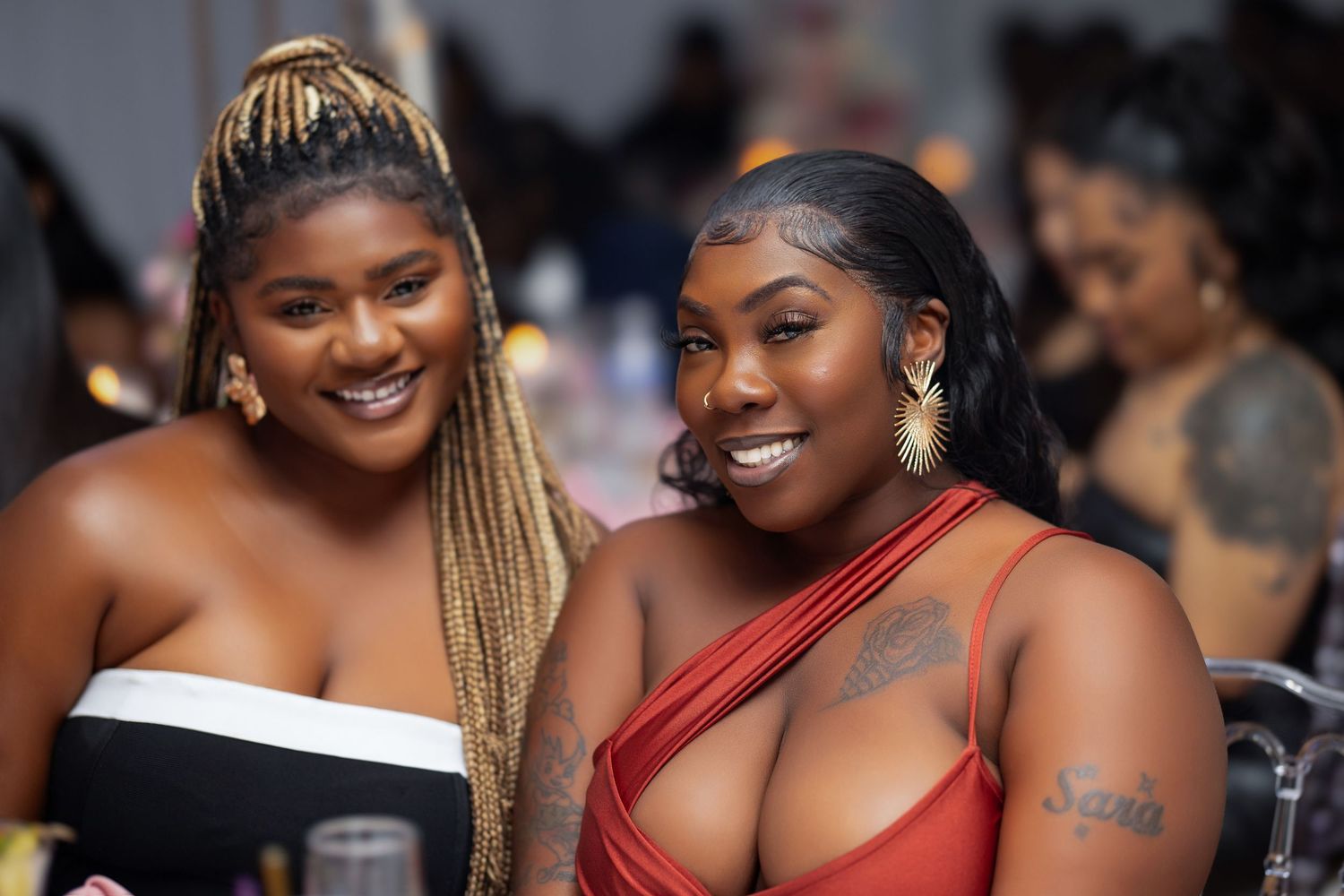 A group of women in formal attire smile and laugh together at an elegant evening event.