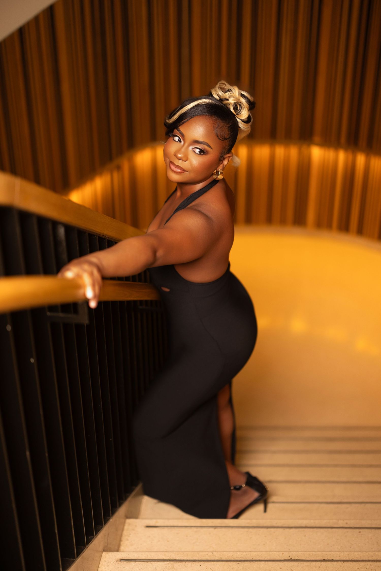 Artistic portrait session on wooden stairs with warm ambient lighting.