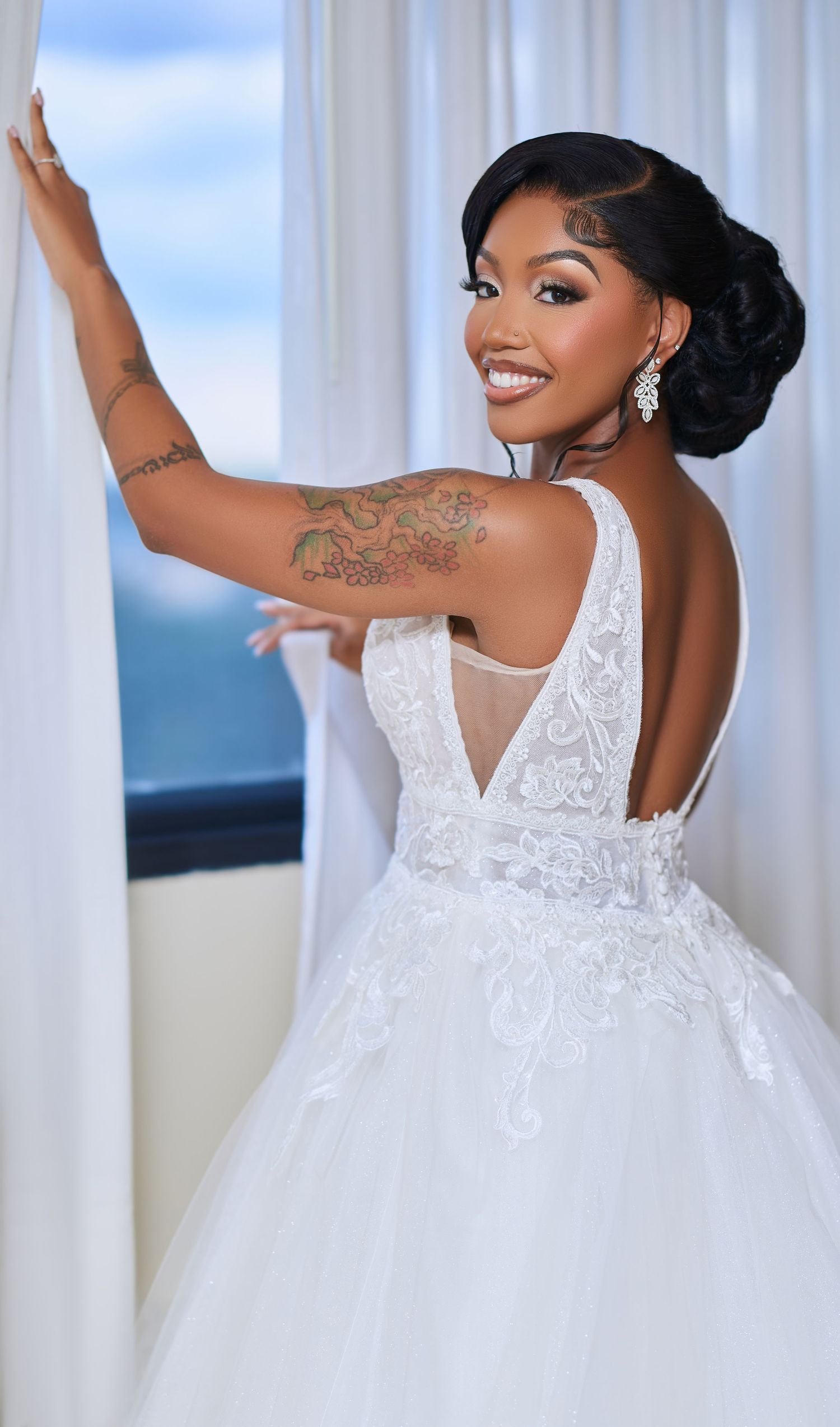 A bride in a white lace ballgown twirls joyfully while showing off her elegant wedding dress and updo hairstyle.