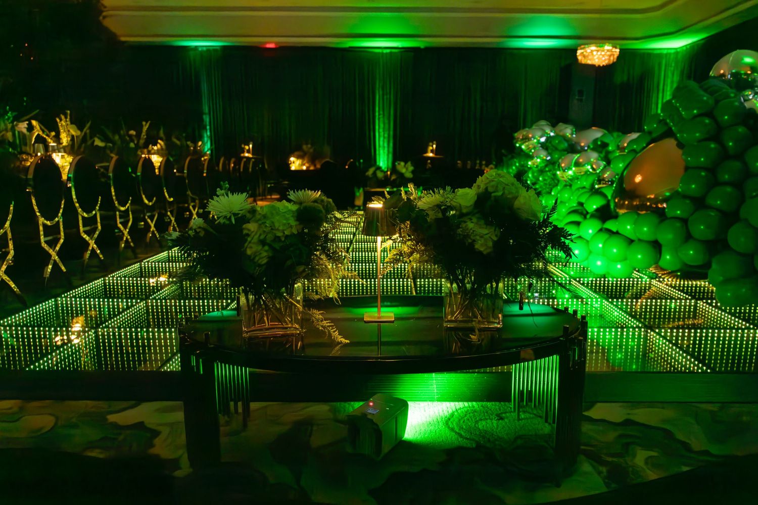 Elegant event space with green lighting and mirrored walkway creating dramatic ambiance.