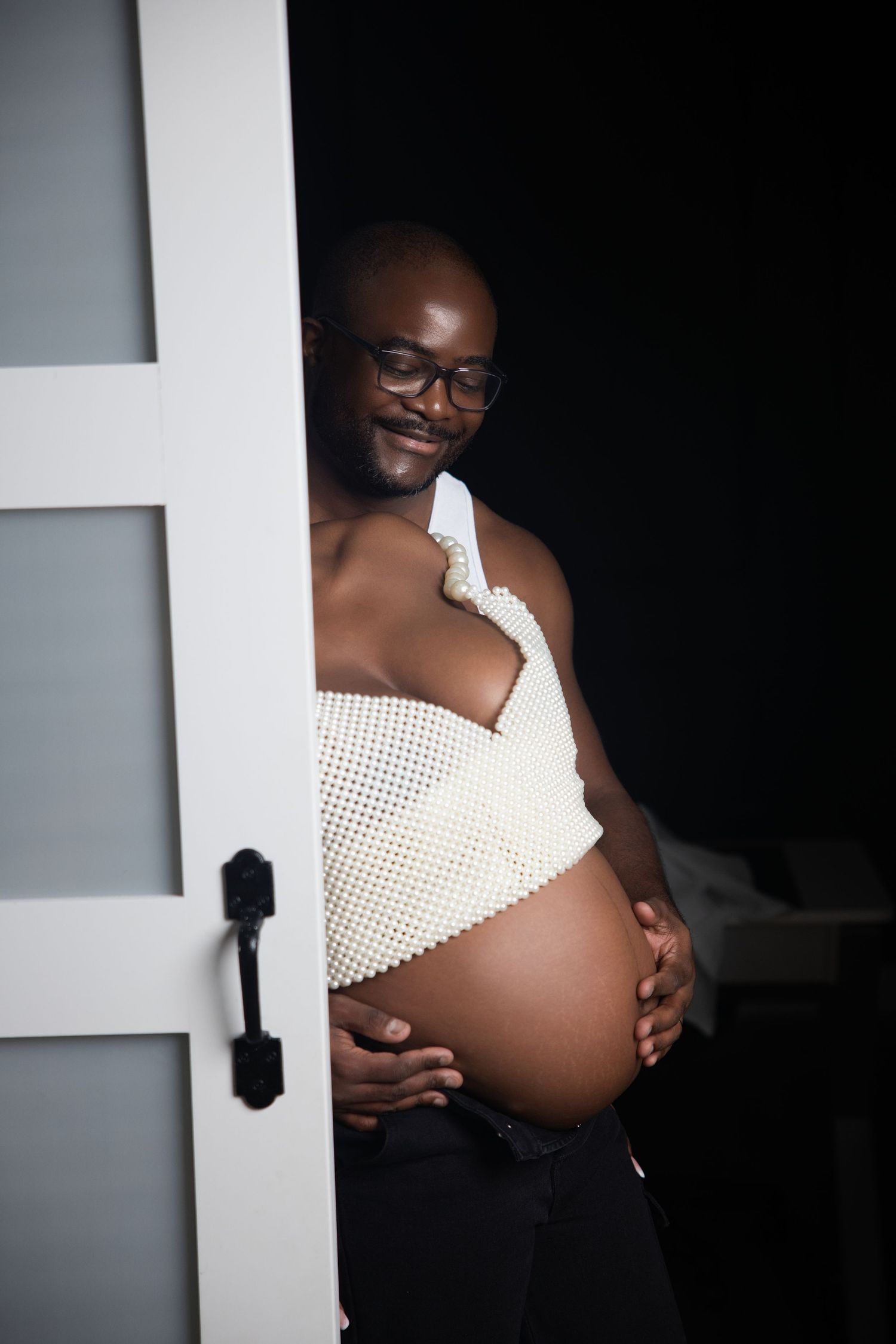 A series of maternity photos showing a pregnant belly in a white polka dot dress against a dark background.