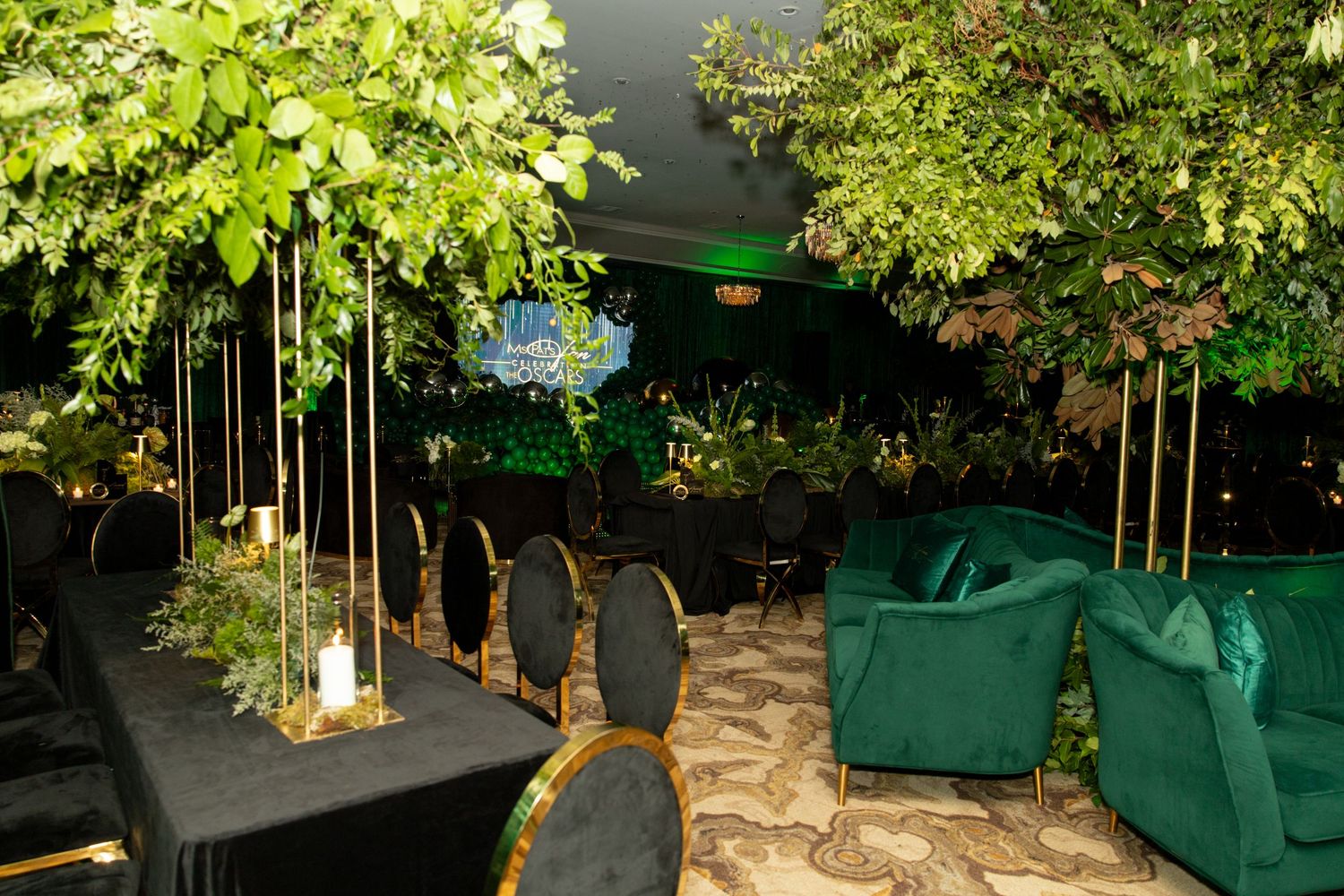 A romantic outdoor garden dining area with lanterns and string lights illuminating tables under lush green foliage.