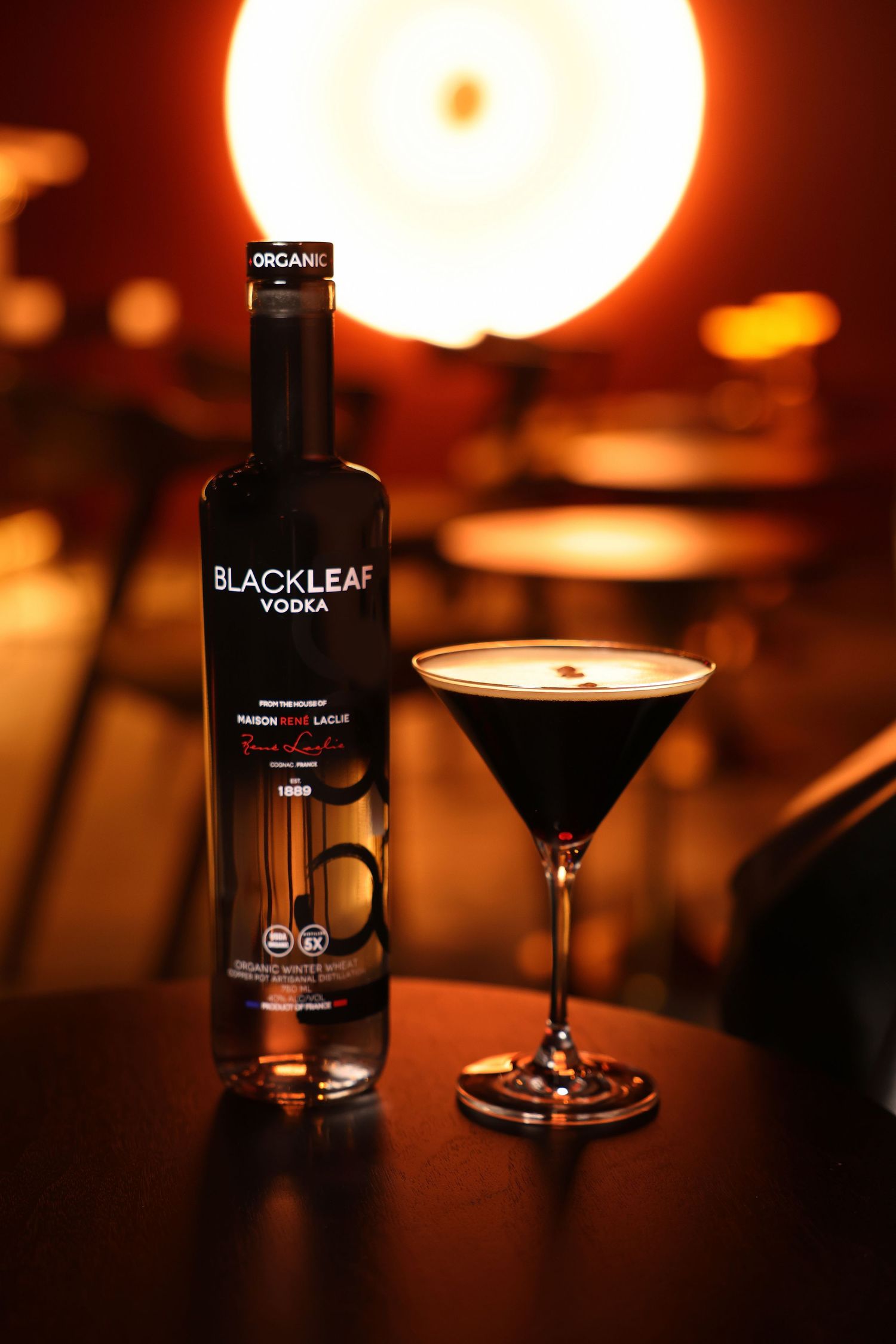 Black Leaf vodka bottle and cocktail glass displayed in atmospheric bar lighting.