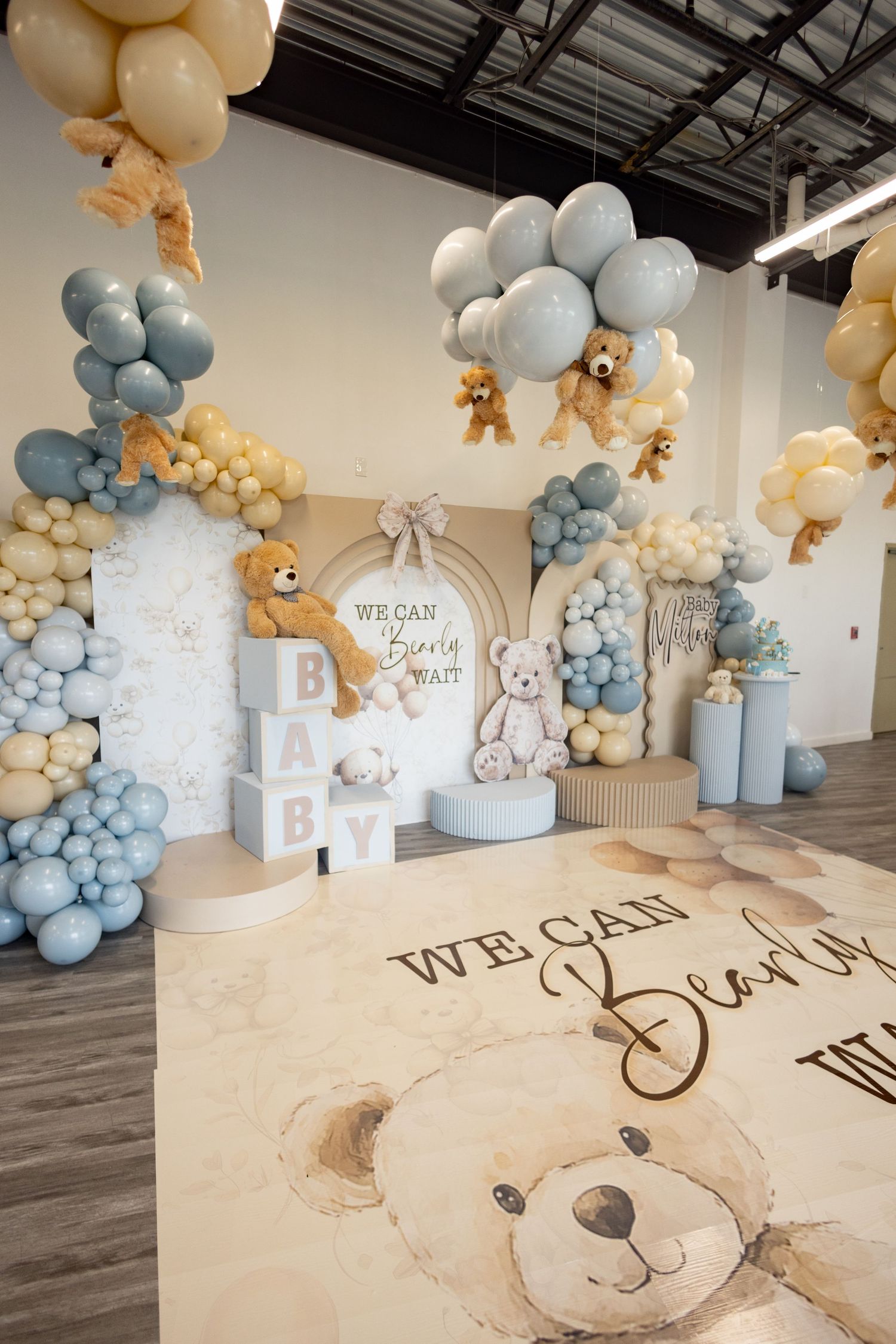 Bear-themed baby shower setup with floor decal and blue balloon arrangements.