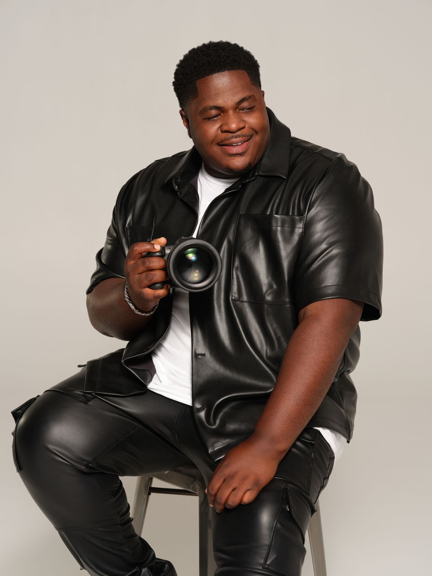 fif wilson  in a black leather jacket poses against a light gray background in a series of four similar photos.