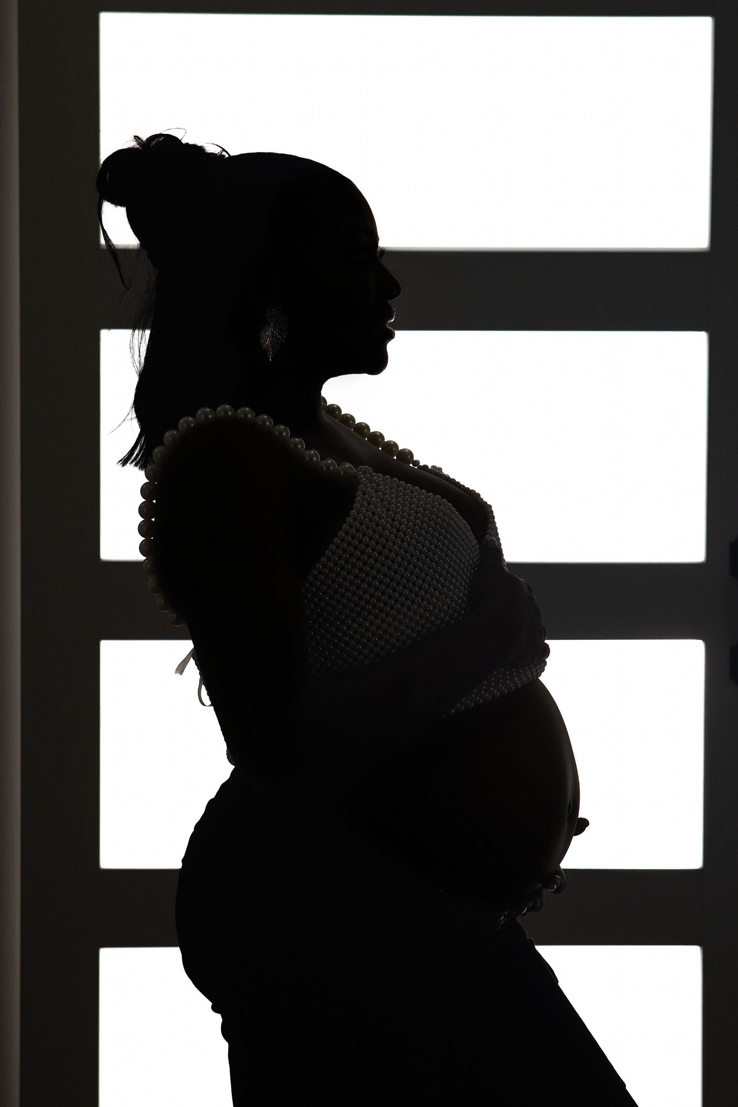Silhouette of a person in profile against bright window panels creating a dramatic contrast effect.