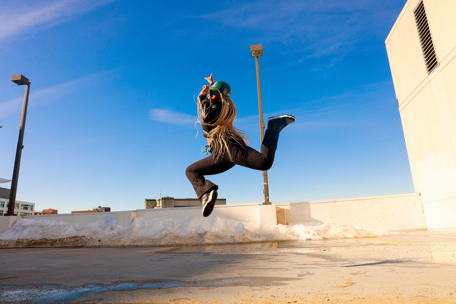 Silhouettes jumping and posing against a bright blue sky at sunset.