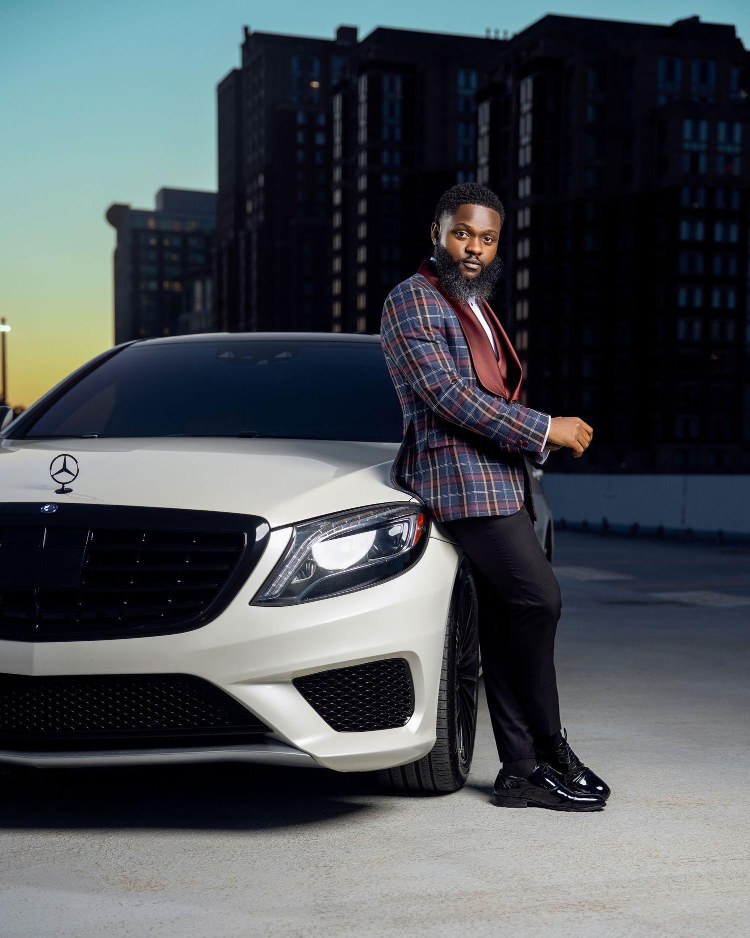 Modern fashion shoot featuring white Mercedes-Benz luxury car against urban skyline.