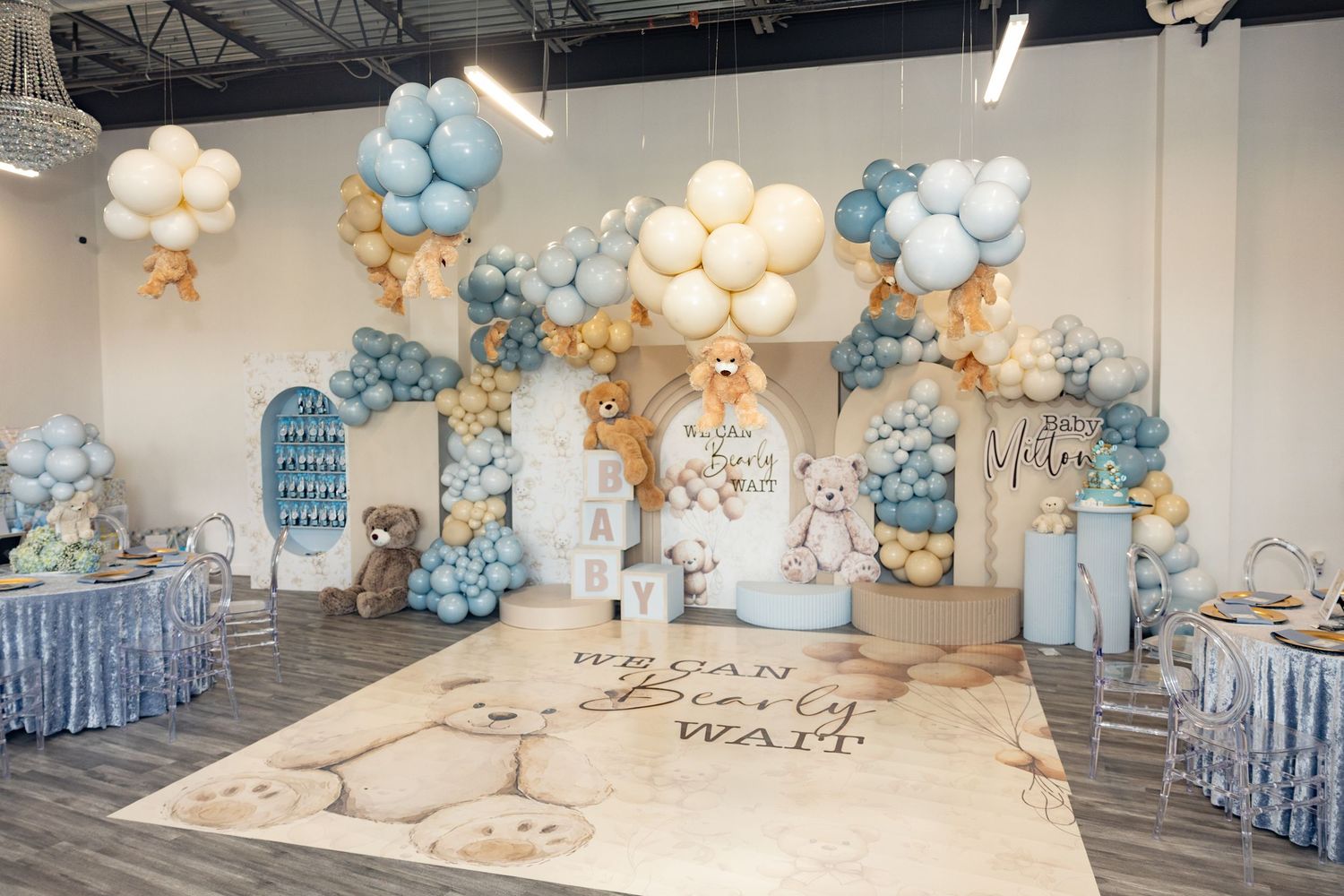 Wide view of baby shower venue with blue and white balloon installations and teddy bear theme.