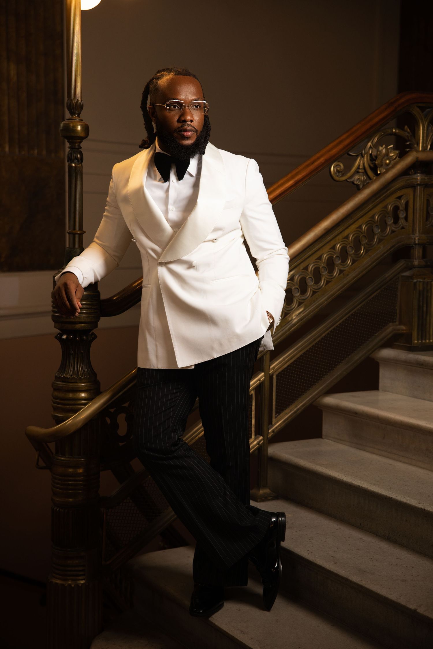 Stylish formal photoshoot on grand staircase featuring elegant white shirt and black pants ensemble.
